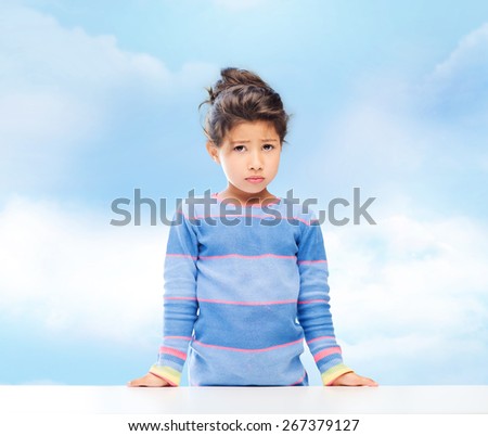 people, childhood and emotions concept - sad little girl over blue sky background