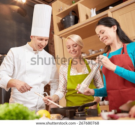cooking class, culinary, food and people concept - happy group of women and male chef cook cooking in kitchen