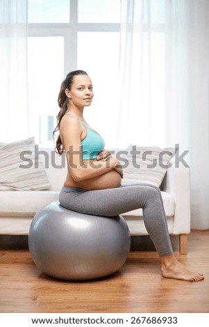 pregnancy, sport, fitness, people and healthy lifestyle concept - happy pregnant woman exercising on fitball at home