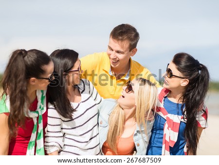summer holidays, vacation, tourism, travel and people concept - group of happy friends having fun and talking on beach