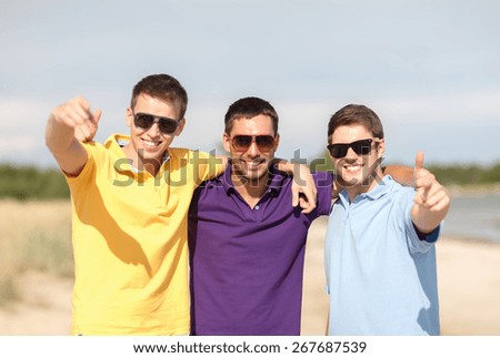 friendship, summer vacation, holidays and people concept - group of smiling male friends in sunglasses showing thumbs up on beach