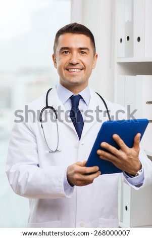 healthcare, technology, profession, people and medicine concept - smiling male doctor in white coat with tablet pc computer in medical office