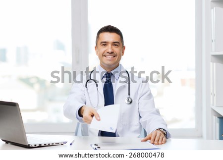 medicine, profession, technology and people concept - happy male doctor with prescription and laptop computer in medical office