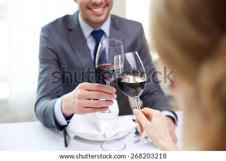 restaurant, people, celebration and holiday concept - close up of young couple with glasses of red wine looking at each other at restaurant
