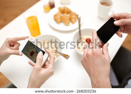 food, eating, people, technology and healthy food concept - close up of couple having breakfast and taking picture of food with smartphones at home