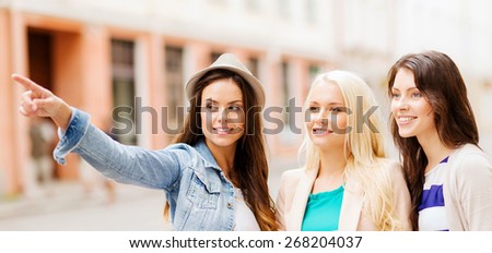 holidays and tourism concept - beautiful girls looking for direction in the city