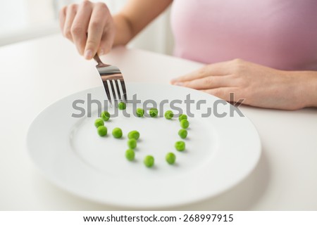 healthy eating, dieting, vegetarian food and people concept - close up of woman with fork eating peas in shape of heart
