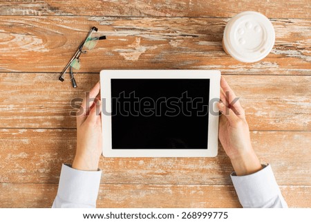 business, education, people and technology concept - close up of female hands holding tablet pc computer with coffee cup and eyeglasses
