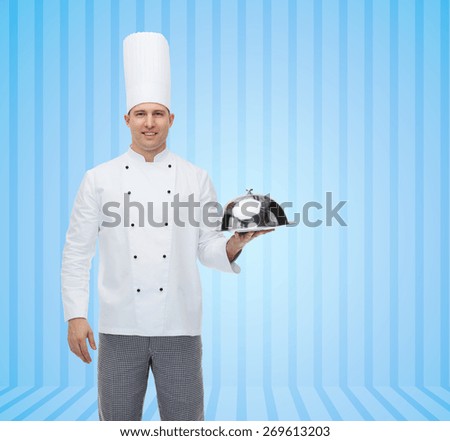 cooking, profession and people concept - happy male chef cook holding cloche over blue striped background