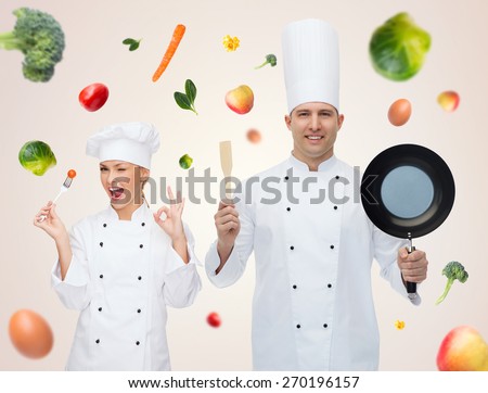 cooking, profession, vegetarian diet and people concept - happy male chef cook holding frying pan and spatula over beige background with falling vegetables
