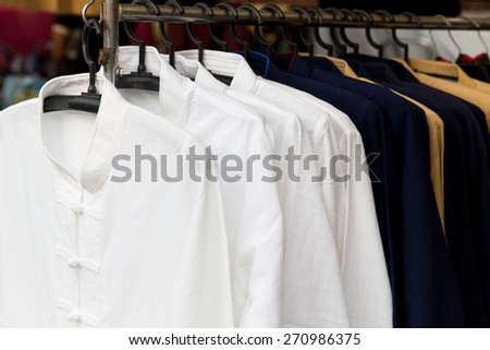 shopping, industry, sale and clothing concept - male oriental shirts on hanger at asian street market