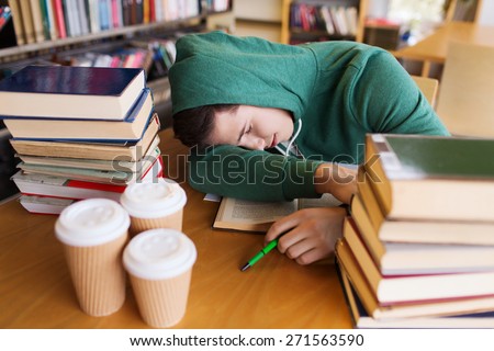 people, education, session, exams and school concept - tired student or young man with books and coffee sleeping in library