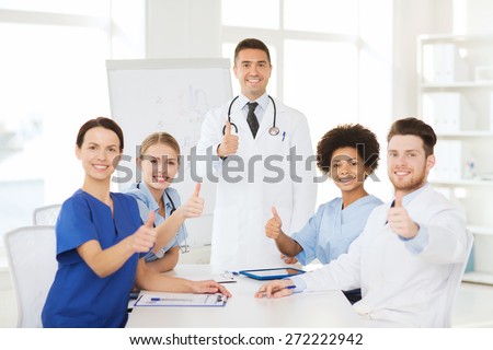 hospital, profession, medical education, people and medicine concept - group of happy doctors meeting on presentation or conference at hospital and showing thumbs up gesture