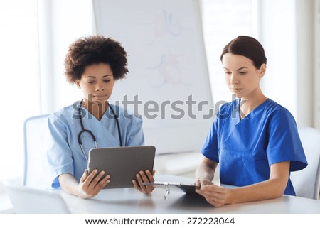 hospital, profession, people and medicine concept - doctors with tablet pc computer and clipboard meeting at medical office