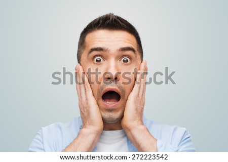 fear, emotions, horror and people concept - scared man shouting and touching his face over gray background