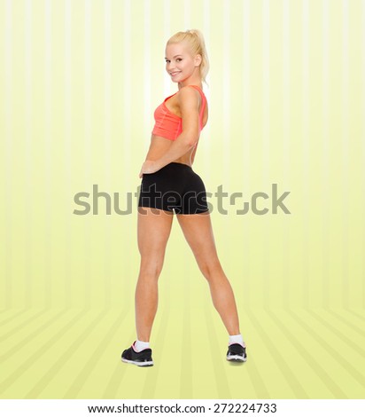 fitness, sport and people concept - beautiful athletic woman in sportswear from back over yellow striped background