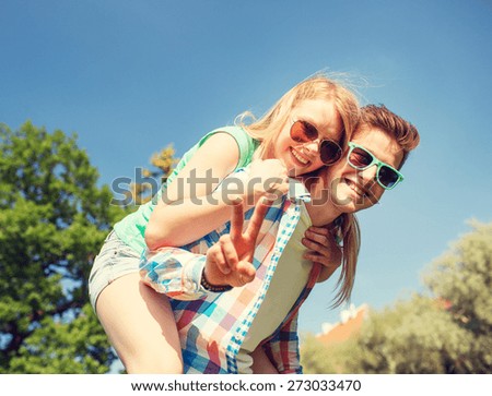 holidays, vacation, love, gesture and friendship concept - smiling couple having fun and showing peace or victory sign in park