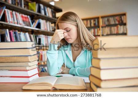 people, knowledge, education, literature and school concept - bored student girl or young woman with books dreaming in library