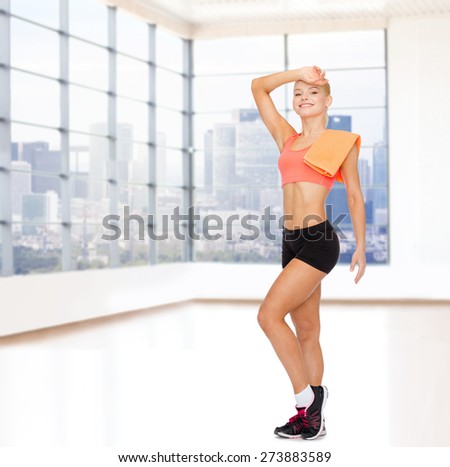 sport, fitness, people and workout concept - smiling sporty woman with towel wiping off sweat over gym background
