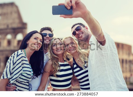 summer, europe, tourism, technology and people concept - group of smiling friends taking selfie with smartphone over coliseum background