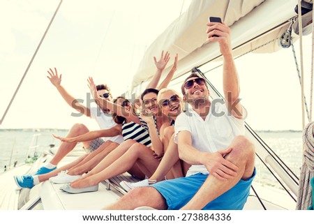 vacation, travel, sea, friendship and people concept - smiling friends sitting on yacht deck and making selfie