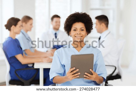 clinic, profession, people and medicine concept - happy female doctor or nurse with tablet pc computer over group of medics meeting at hospital