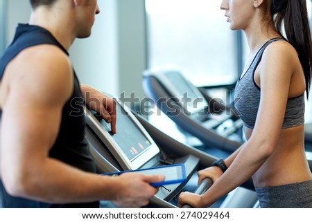 sport, fitness, lifestyle, technology and people concept - close up of woman with trainer working out on treadmill in gym