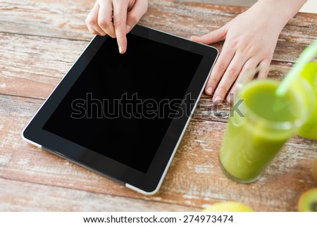 healthy eating, technology, diet and people concept - close up of woman hands with tablet pc, fruits and fresh juice sitting at table
