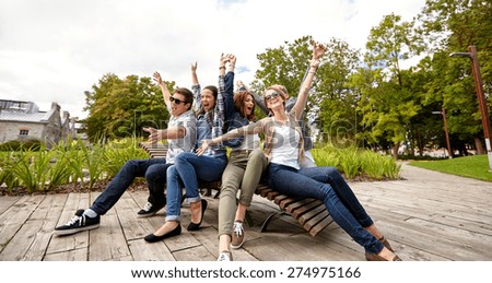 summer holidays, friendship, leisure and teenage concept - group of students or teenagers hanging out and waving hands at campus or park
