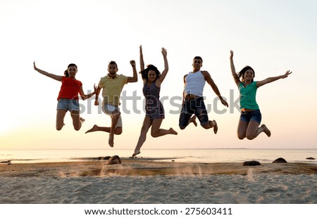 friendship, summer vacation, holidays, party and people concept - group of smiling friends dancing and jumping on beach
