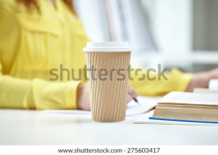 people and education concept - close up of female hands with books and coffee cup