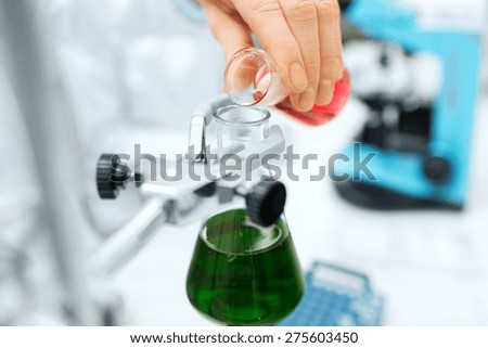 science, chemistry, biology, medicine and people concept - close up of scientist hand filling test tubes and making research in clinical laboratory