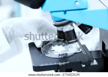 science, chemistry, biology, medicine and people concept - close up of scientist hand with microscope and powder test sample making research in clinical laboratory