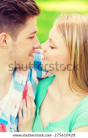 holidays, vacation, love and friendship concept - smiling couple touching noses in park
