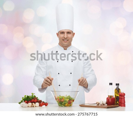profession, vegetarian, food and people concept - happy male chef cooking vegetable salad over blue lights background