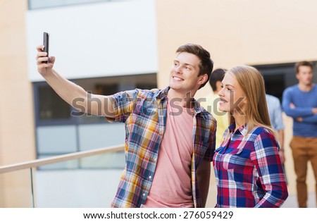 friendship, people, technology and education concept - group of smiling students with smartphone taking selfie outdoors