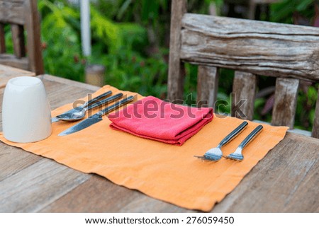 table setting, silverware and eating concept - close up of cutlery with glass and napkin on restaurant table