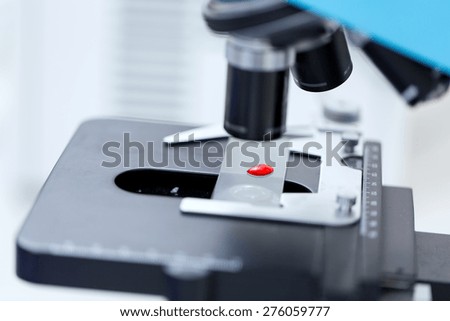 science, chemistry, biology, medicine and research concept - close up of microscope with blood test sample in clinical laboratory