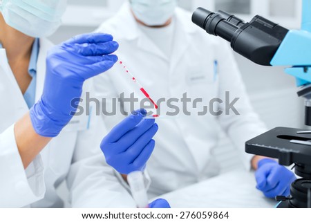 science, chemistry, technology, biology and people concept - close up of scientists hands with pipette and petri dish making research in clinical laboratory