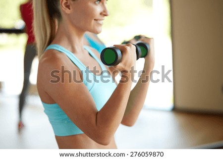 fitness, sport, training, people and lifestyle concept - closeup of woman with dumbbells flexing muscles in gym