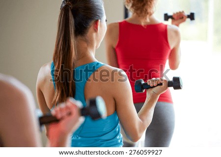 fitness, sport, training, people and lifestyle concept - close up of women working out with dumbbells and flexing muscles in gym