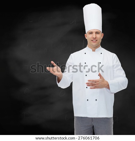 cooking, profession and people concept - happy male chef cook inviting over black chalk board background