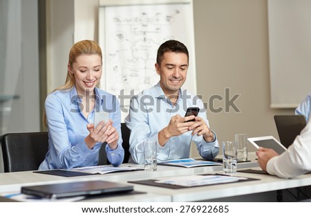 business, people and technology concept - smiling business team with smartphones meeting in office