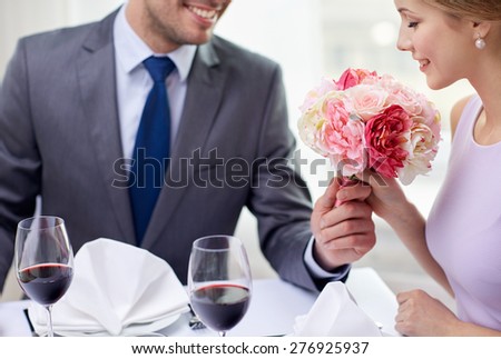 restaurant, people, celebration and holiday concept - smiling young couple with glasses of red wine looking at each other at restaurant