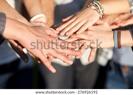 friendship, togetherness, team and people concept - close up of students or teenagers with hands outdoors