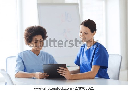 hospital, profession, people and medicine concept - group of happy doctors with tablet pc computer and clipboard meeting at medical office