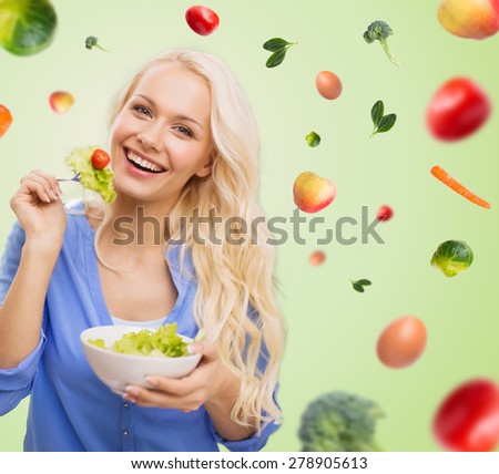 people, healthy eating, dieting and food concept - smiling young woman eating vegetable salad over green background