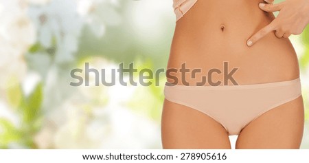 people, beauty, health and body care concept - close up of woman pointing finger at her abs over green background