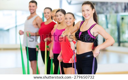 fitness, sport, training, gym and lifestyle concept - group of smiling people working out with rubber bands in the gym