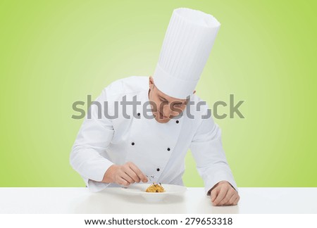 cooking, profession, haute cuisine, food and people concept - happy male chef cook decorating dish over green background